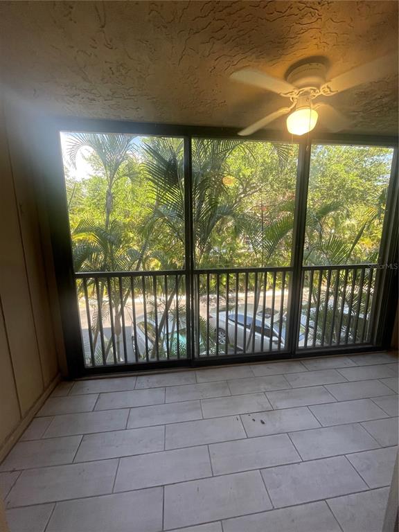 A screened-in balcony features a ceiling fan, tiled flooring, and a view of parked cars — 3700 S OSPREY AVENUE UNIT 216, SARASOTA, FL