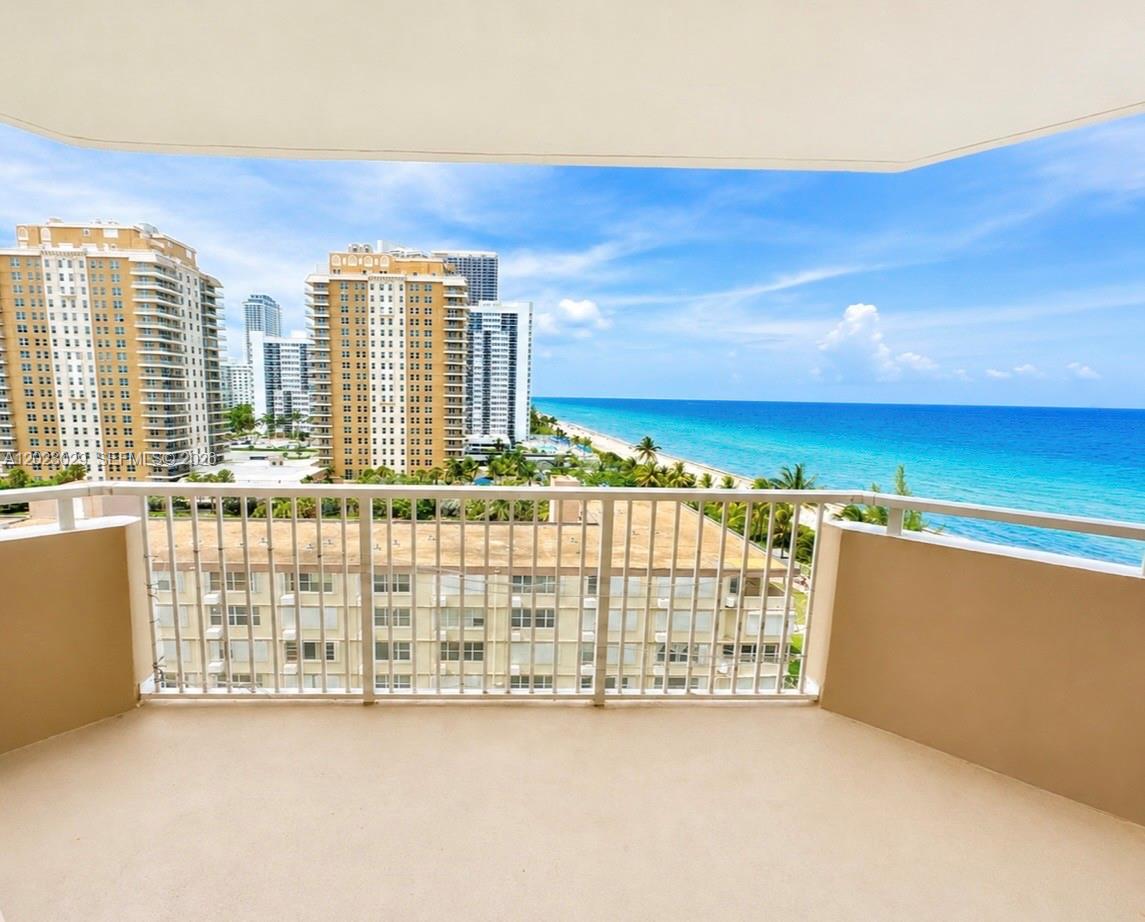 A balcony with a white metal railing overlooks a beach, ocean, and city skyline — 1950 S Ocean Dr # 8K, Hallandale Beach FL 33009, HALLANDALE BEACH, FL