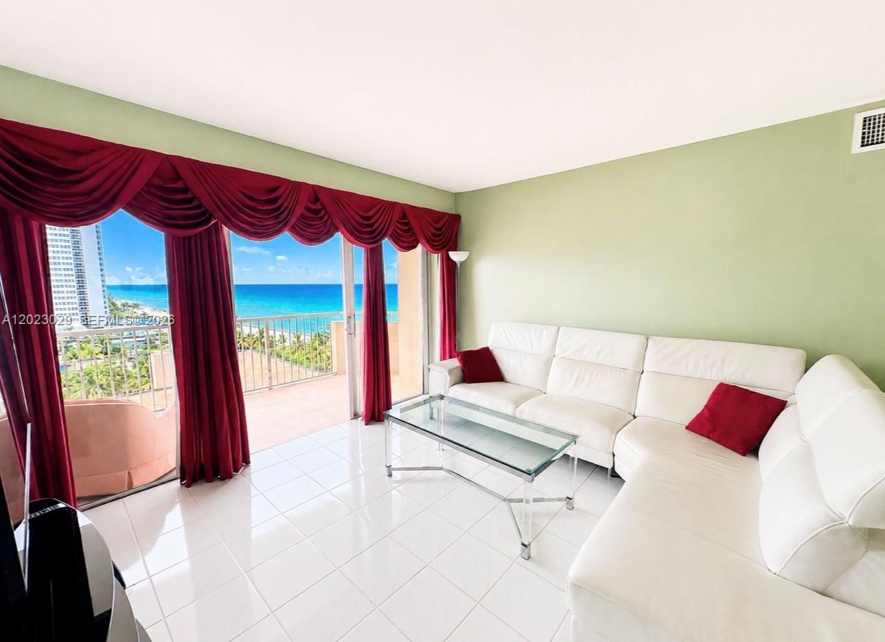 A living room features white tile floors, a white sectional sofa, and floor-to-ceiling ocean views — 1950 S Ocean Dr # 8K, Hallandale Beach FL 33009, HALLANDALE BEACH, FL