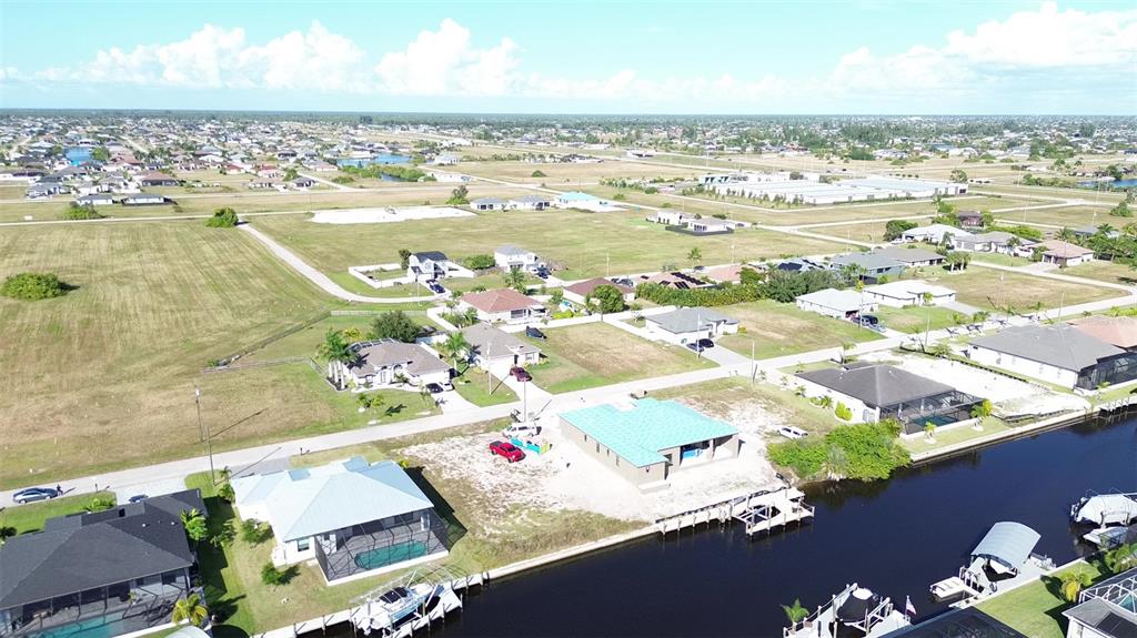An aerial view shows several houses with pools along a canal in a suburban area — 3405 NW 6TH STREET, CAPE CORAL, FL