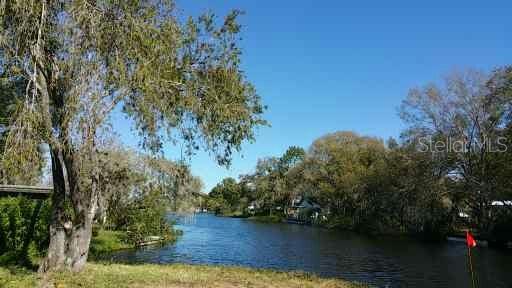 A view of a narrow canal lined with trees under a clear blue sky — 3366 MAPLE LANE, HAINES CITY, FL