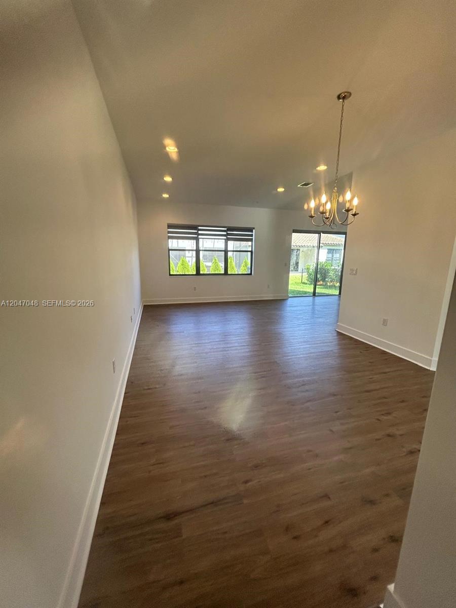 An open-concept dining area features wood-look flooring, a chandelier, and a sliding glass door — 5525 AGOSTINO WAY, Ave Maria FL 34142, AVE MARIA, FL
