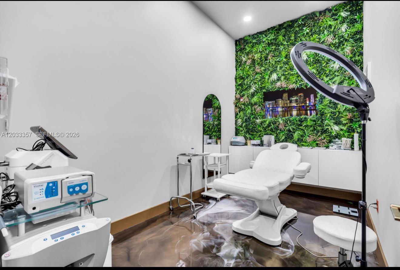 A treatment room features a white medical chair, a ring light, and a green wall — MIAMI, FL