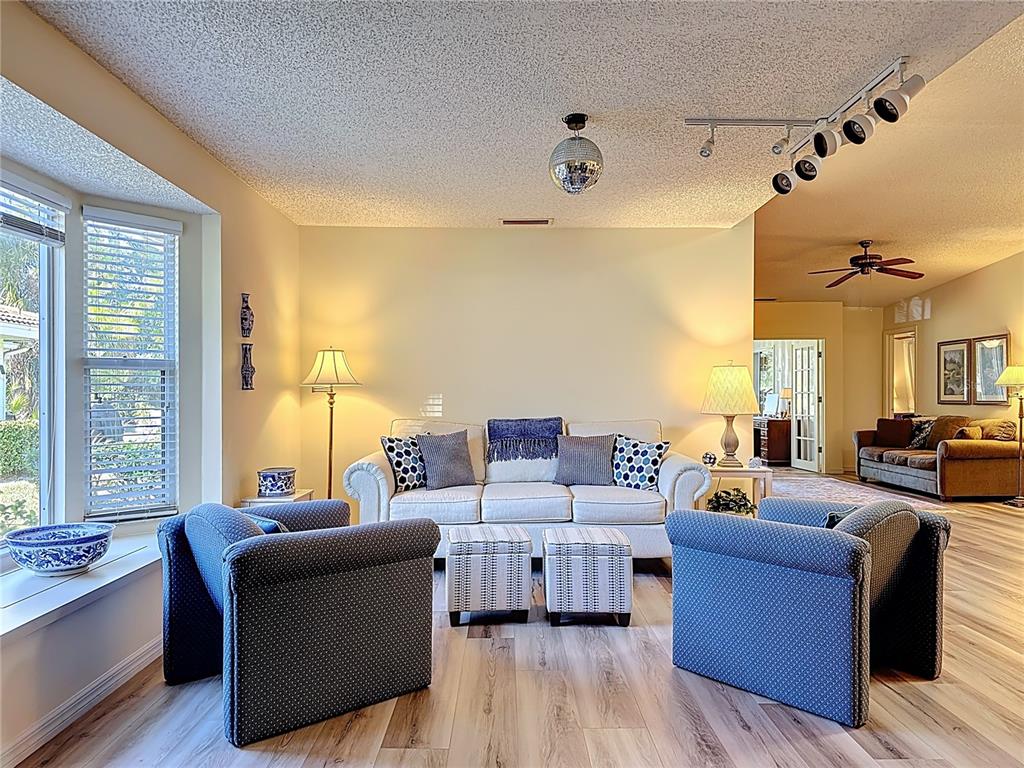 A living room features a white sofa, two blue armchairs, and a disco ball light — 5611 GARDEN LAKES DRIVE, BRADENTON, FL