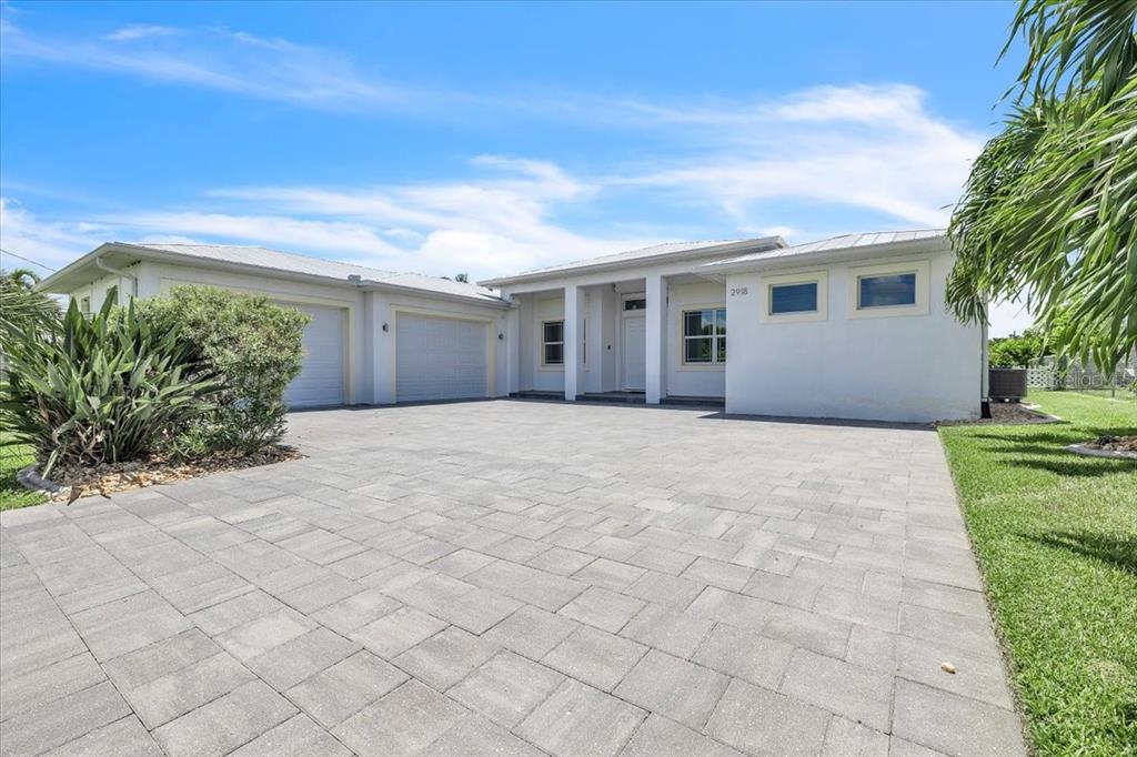 A single-story house with a paved driveway, two garage doors, and a white exterior — 2918 SE 10TH PLACE, CAPE CORAL, FL