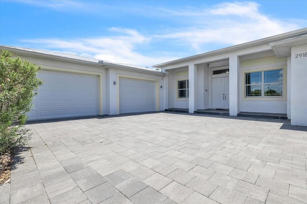 A white house with a paved driveway, two garage doors, and a covered front entrance — 2918 SE 10TH PLACE, CAPE CORAL, FL