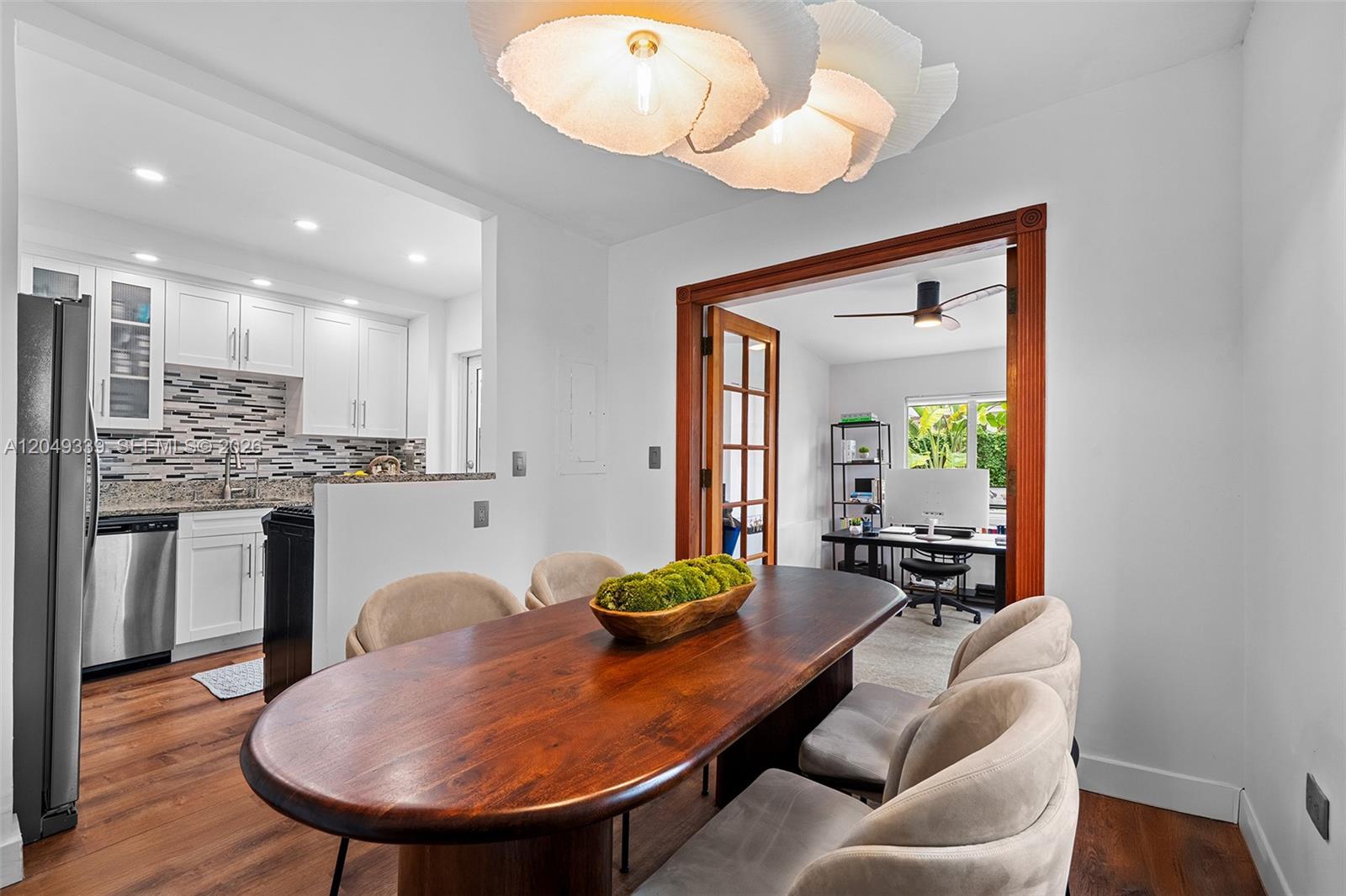 A dining area with a wooden table and chairs sits adjacent to a kitchen — 642 86th St, Miami Beach FL 33141, MIAMI BEACH, FL