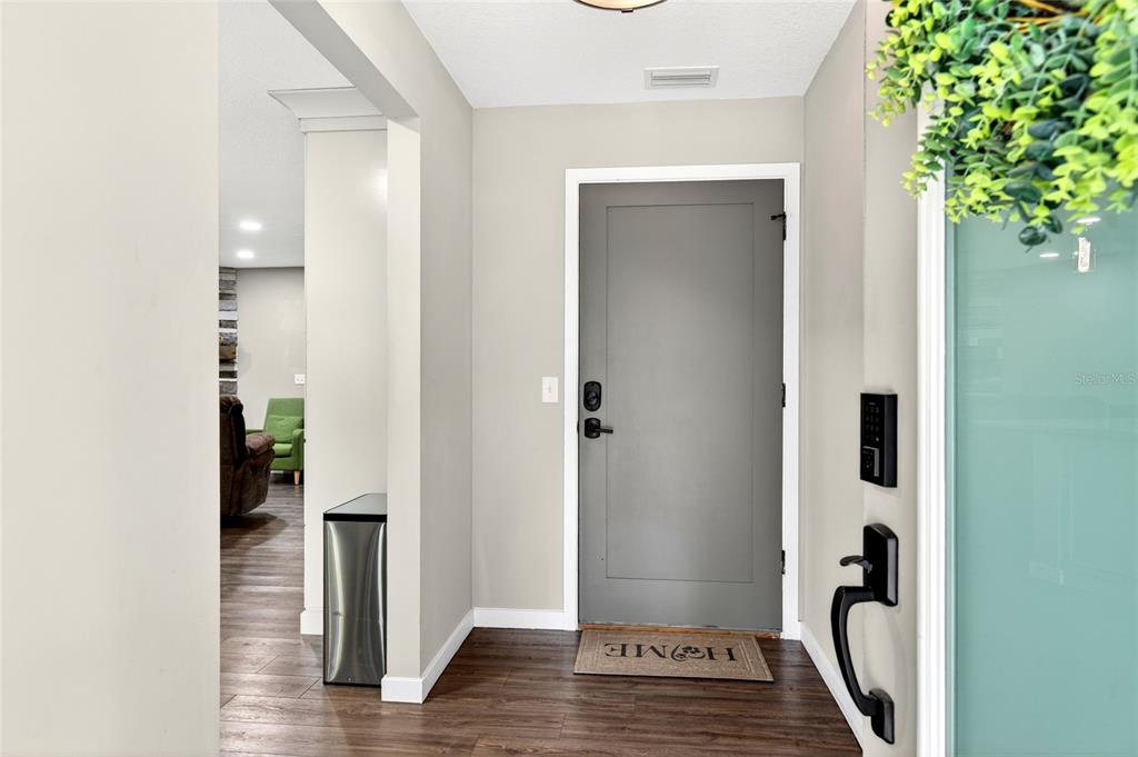 An entryway features a gray front door, wood-look flooring, and a view into a living area — 14271 NE 47TH AVENUE, ANTHONY, FL