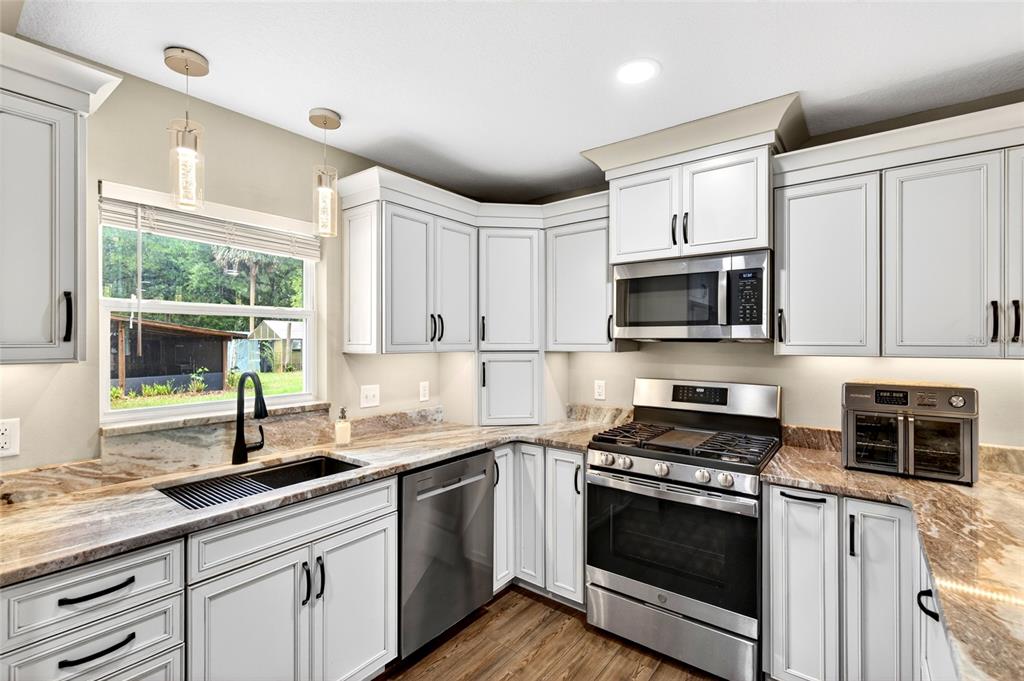 A kitchen features white cabinetry, stainless steel appliances, and brown granite countertops — 14271 NE 47TH AVENUE, ANTHONY, FL
