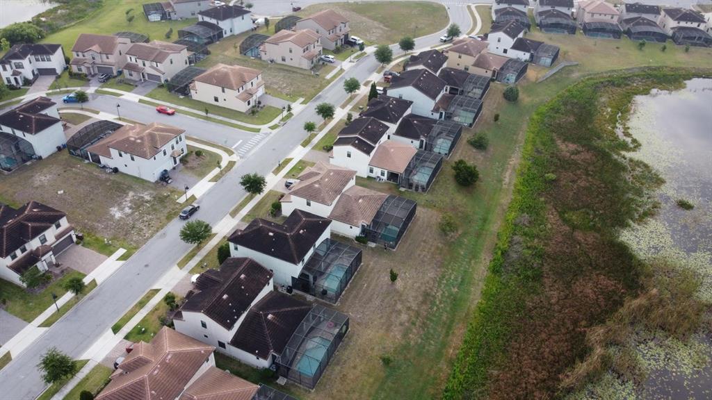 An aerial view shows a suburban neighborhood with houses, swimming pools, and a nearby lake — 179 MITCHELLS MANOR, HAINES CITY, FL