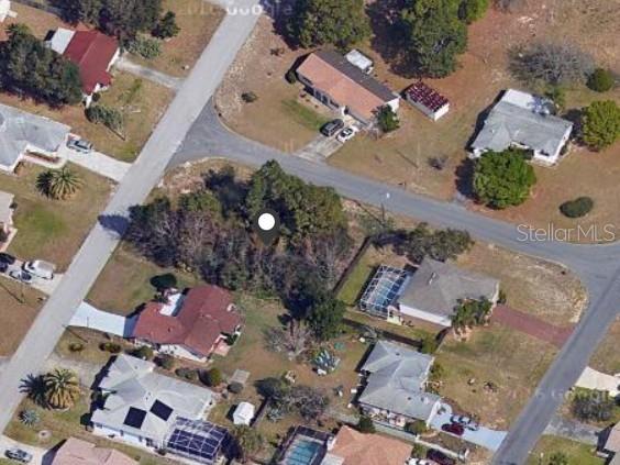 An aerial view shows a vacant, tree-covered lot surrounded by residential houses and paved streets — 11416 ADELIA STREET, SPRING HILL, FL