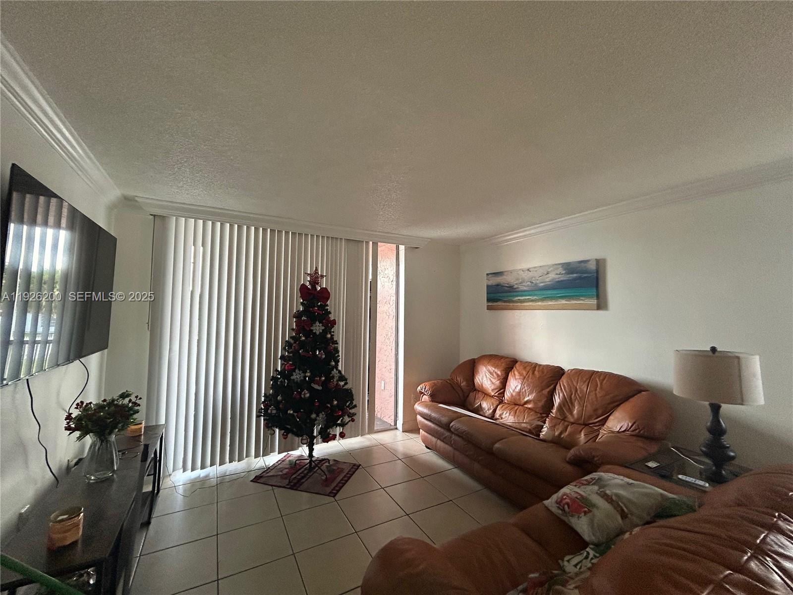 A living room features tile floors, a brown leather sofa, and a decorated Christmas tree — 19805 SW 114th Ave # 219, Miami FL 33157, MIAMI, FL