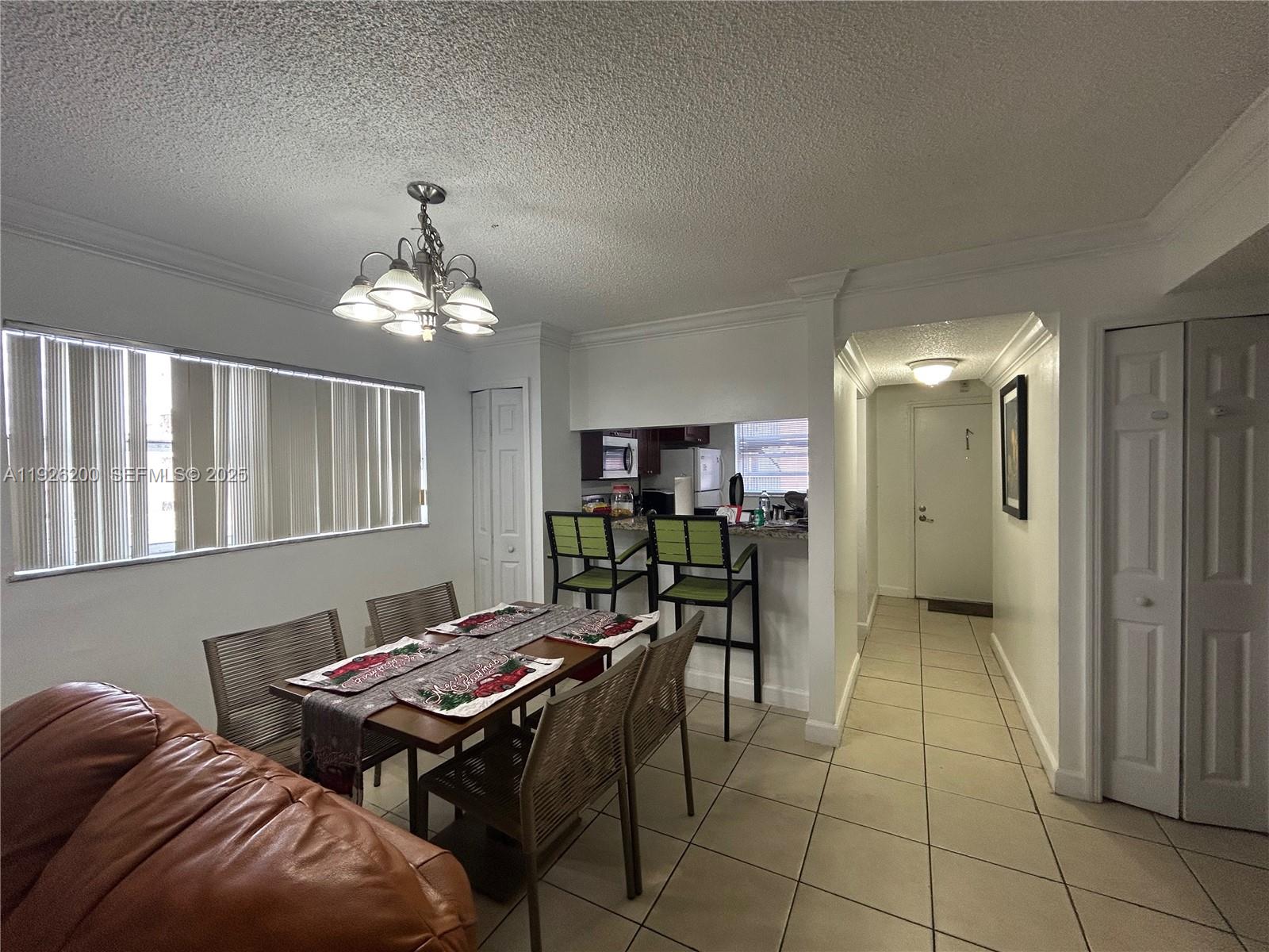 A dining area with a table and chairs sits adjacent to a kitchen breakfast bar — 19805 SW 114th Ave # 219, Miami FL 33157, MIAMI, FL
