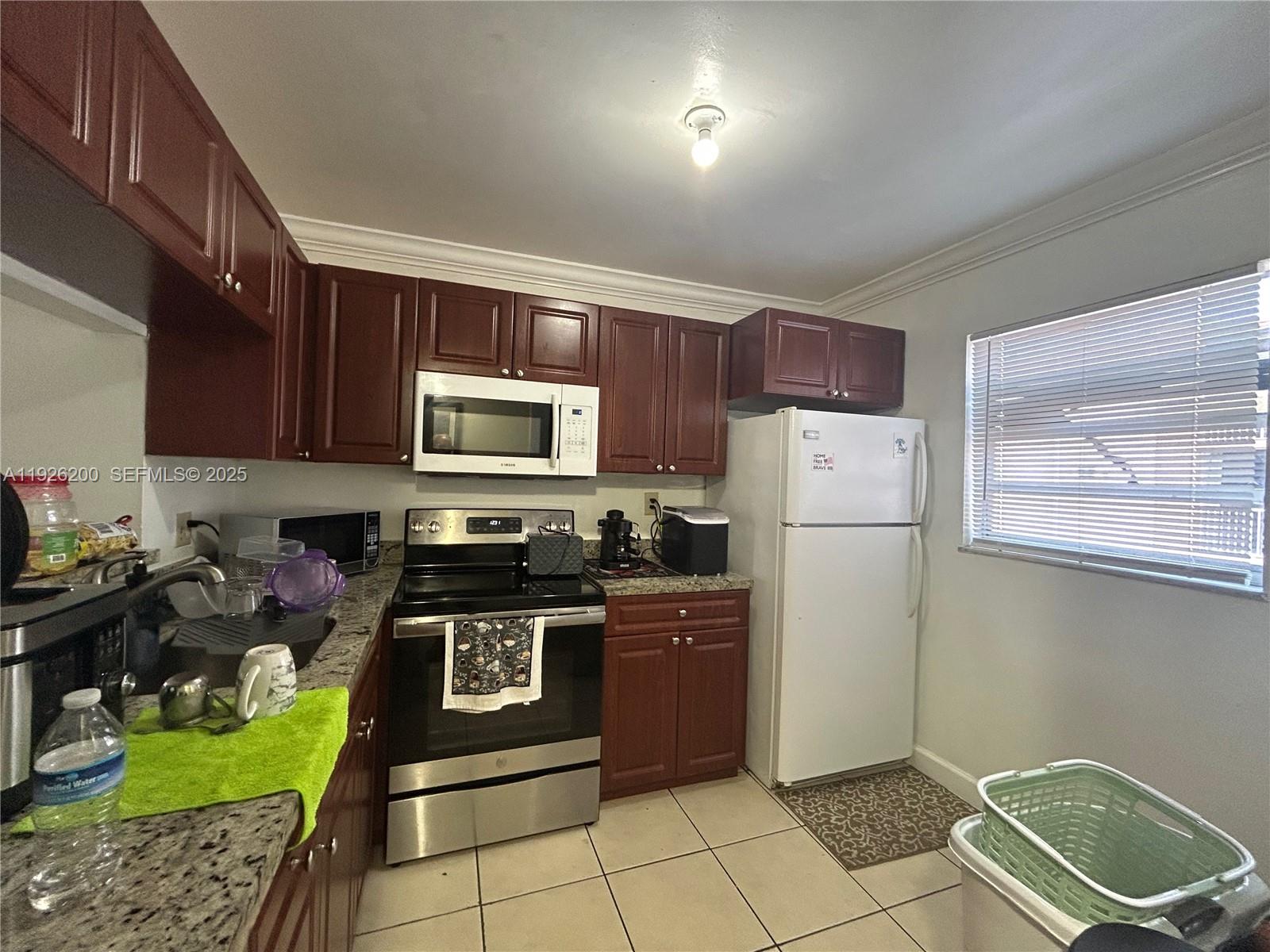A kitchen features dark wood cabinets, stainless steel appliances, granite countertops, and tile flooring — 19805 SW 114th Ave # 219, Miami FL 33157, MIAMI, FL