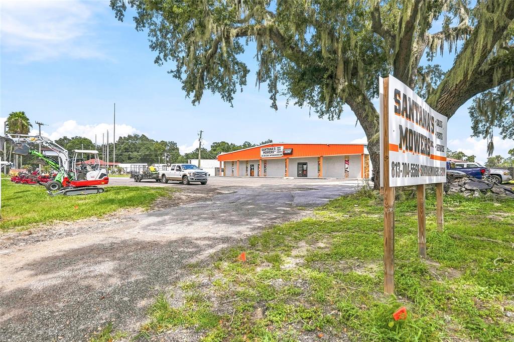 An exterior view of Santana's Mowers with a large sign, parking lot, and equipment — 13295 92 HIGHWAY, DOVER, FL
