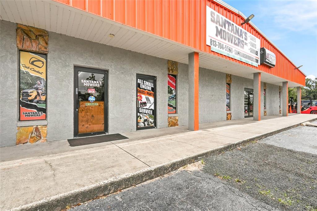 The exterior of a commercial building features a gray facade, orange trim, and signage for a mower shop — 13295 92 HIGHWAY, DOVER, FL