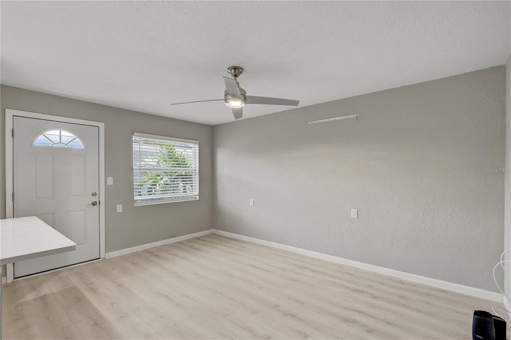 A room with light wood-look flooring, gray walls, a ceiling fan, and a white door — 9030 BLIND PASS ROAD UNIT C9, TREASURE ISLAND, FL