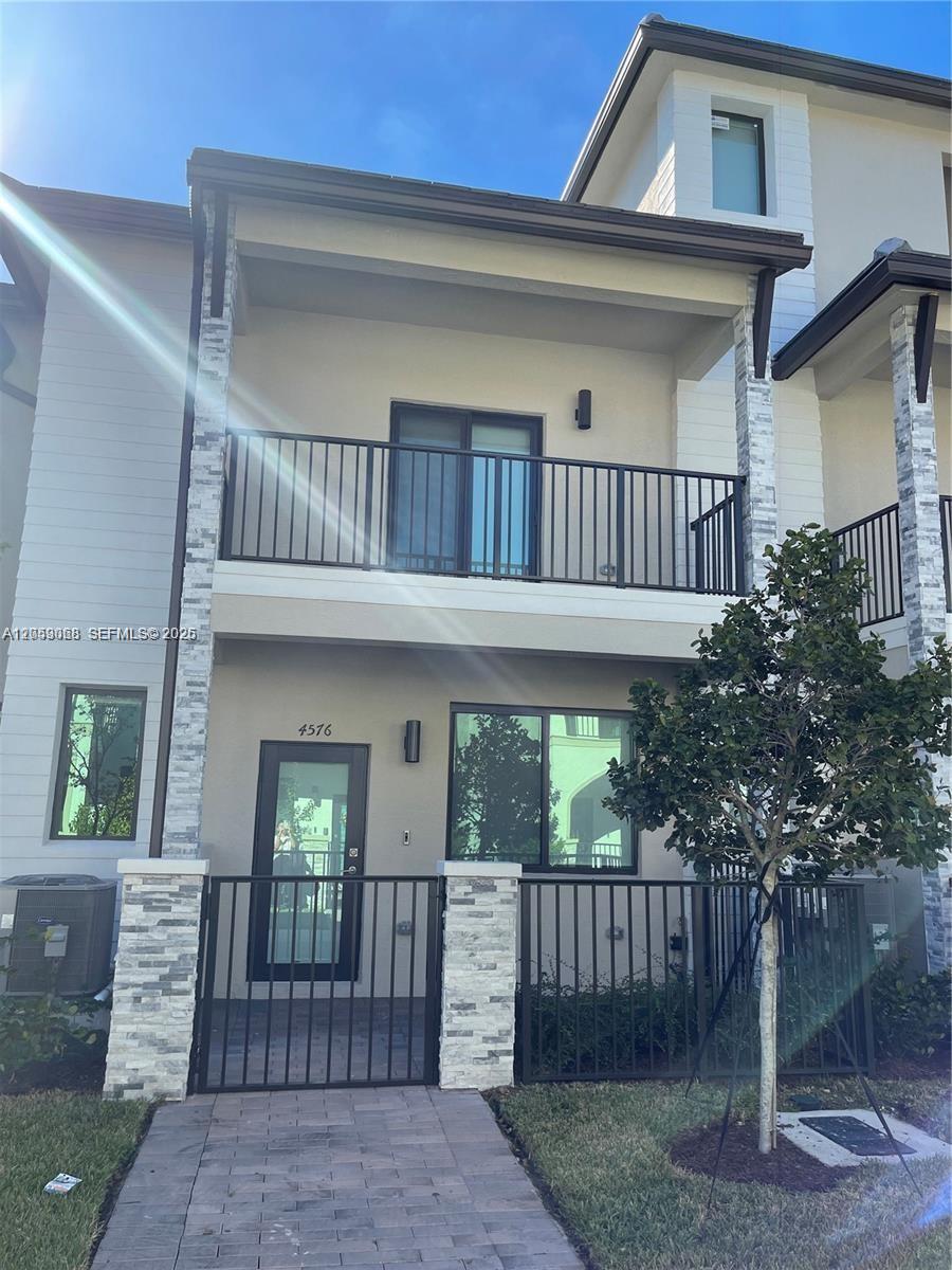 A two-story townhouse exterior features a stone-accented facade, a balcony, and a gated entrance — 4576 NW 83rd Path, Doral FL 33166, DORAL, FL