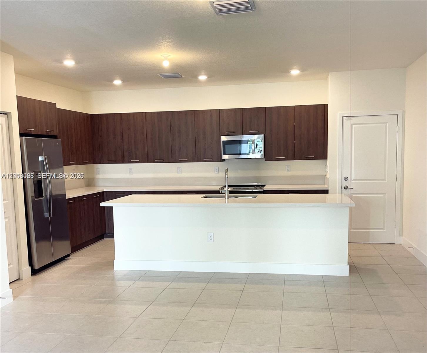 A kitchen features dark wood cabinets, stainless steel appliances, and a white quartz island — 4576 NW 83rd Path, Doral FL 33166, DORAL, FL