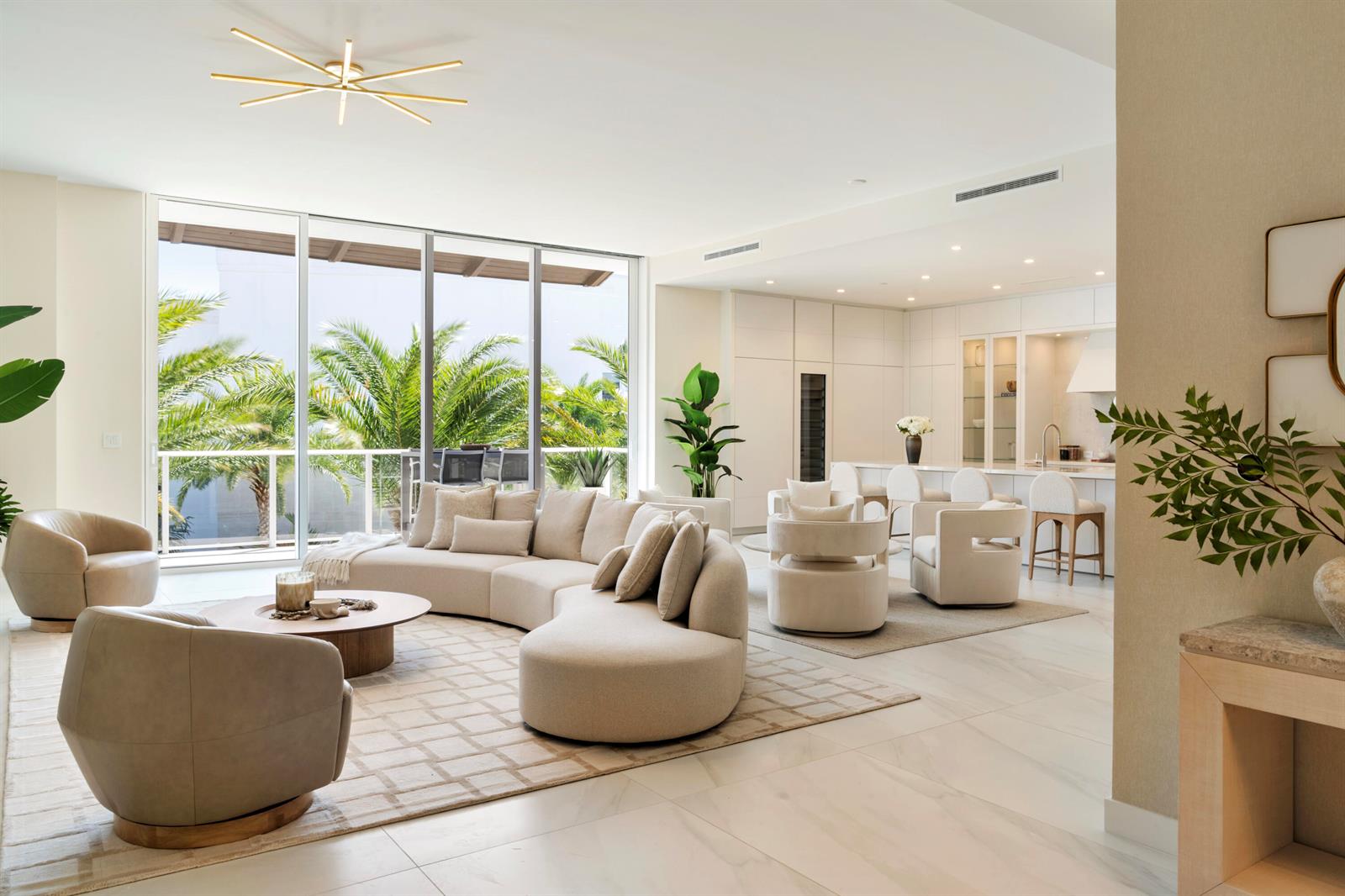 A modern open-concept living room features a curved sofa, neutral furniture, and floor-to-ceiling windows — 220 SE Mizner Boulevard, Boca Raton FL 33432, BOCA RATON, FL