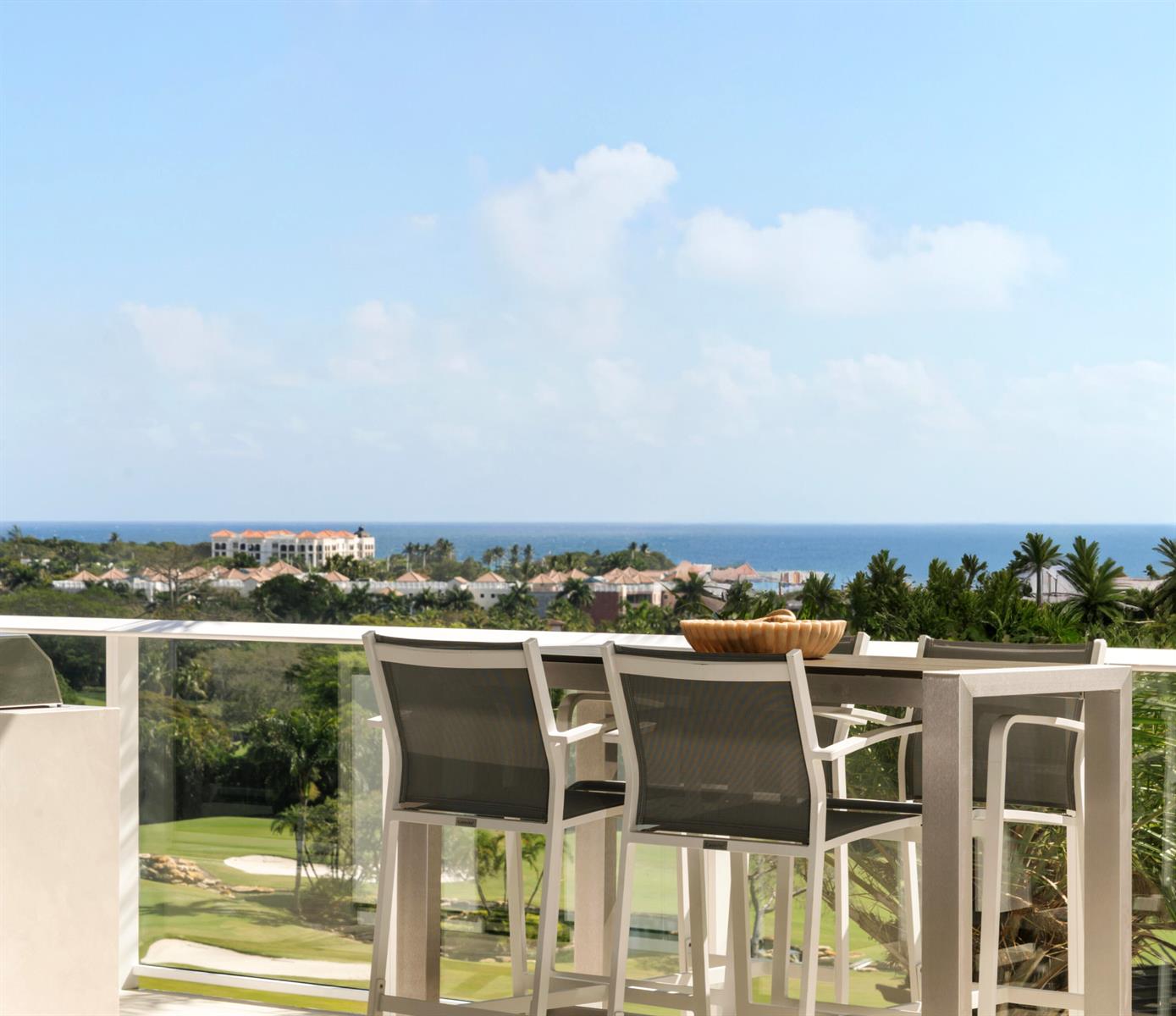 A balcony features a high-top table and chairs overlooking a golf course and the ocean — 220 SE Mizner Boulevard, Boca Raton FL 33432, BOCA RATON, FL