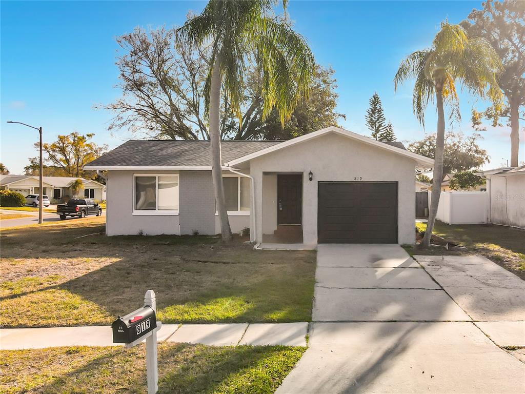 A single-story house with a gray exterior, a garage, and two palm trees in front — 819 HELMSMAN WAY, PALM HARBOR, FL