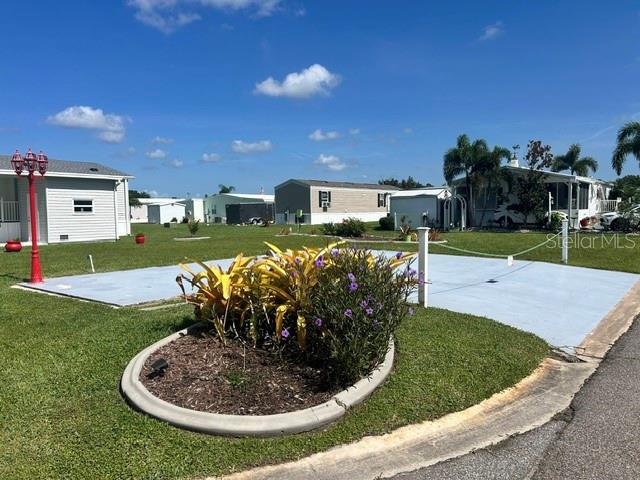 A landscaped garden bed sits in front of a paved patio area in a neighborhood — 267 DOLPHIN PKWY, PUNTA GORDA, FL
