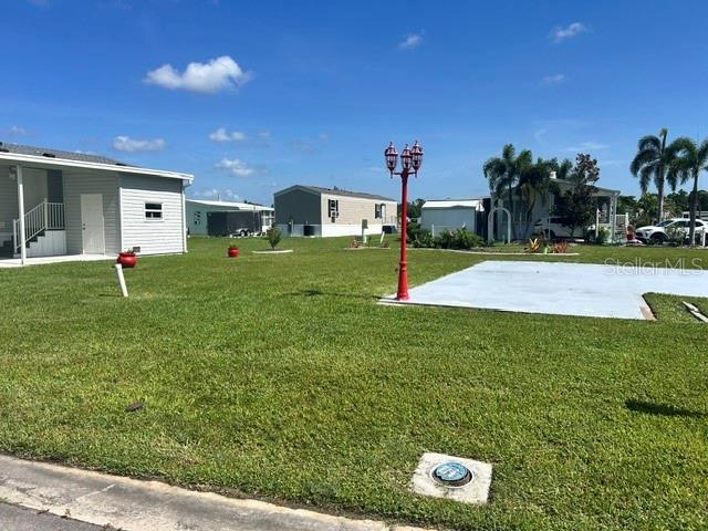 A grassy lot features a red lamp post, a concrete pad, and nearby mobile homes — 267 DOLPHIN PKWY, PUNTA GORDA, FL