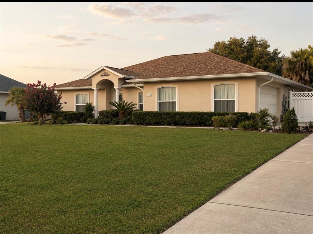 A single-story house with a beige stucco exterior, a shingled roof, and a large lawn — 4025 NE 14TH COURT, OCALA, FL