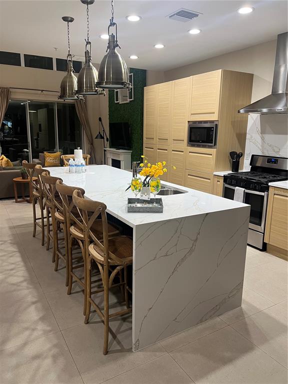 A modern kitchen features a large marble-topped island with wooden bar stools and light cabinetry — 3120 BRASILIA AVENUE, KISSIMMEE, FL