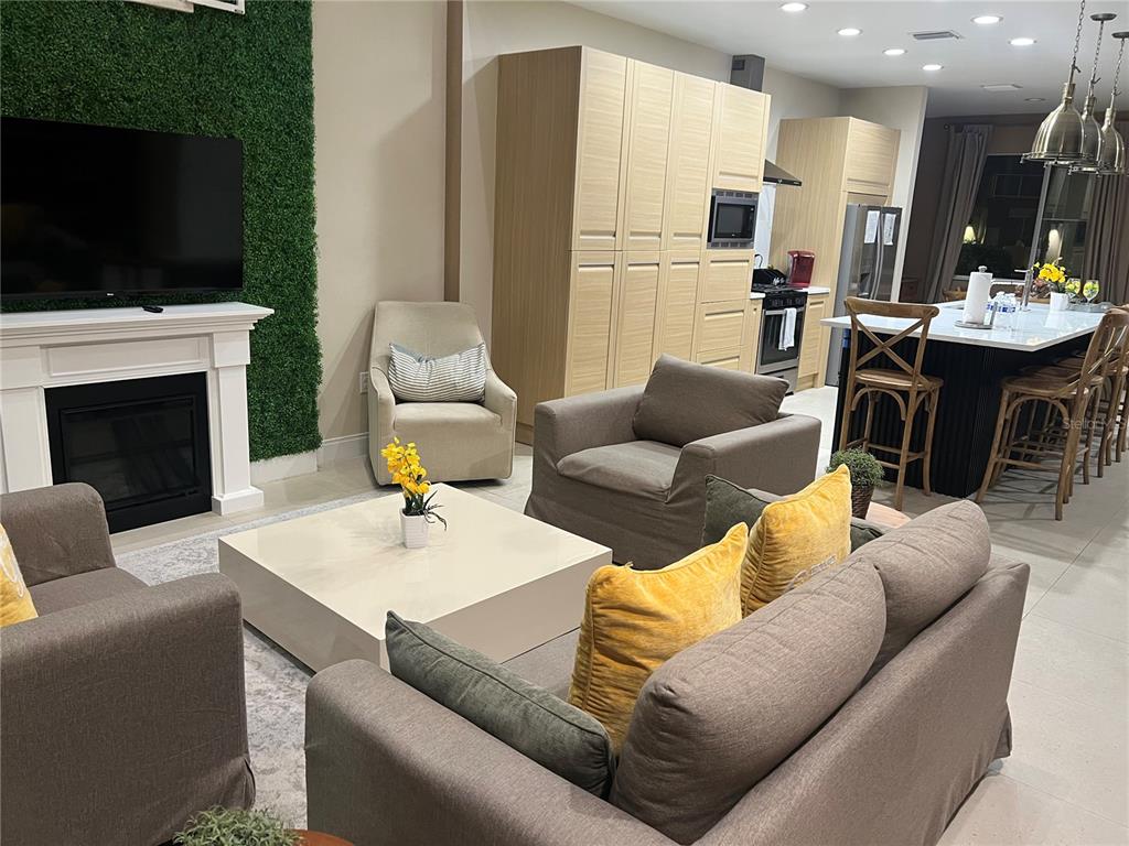 A living room with a fireplace and green wall leads into an open-concept kitchen — 3120 BRASILIA AVENUE, KISSIMMEE, FL
