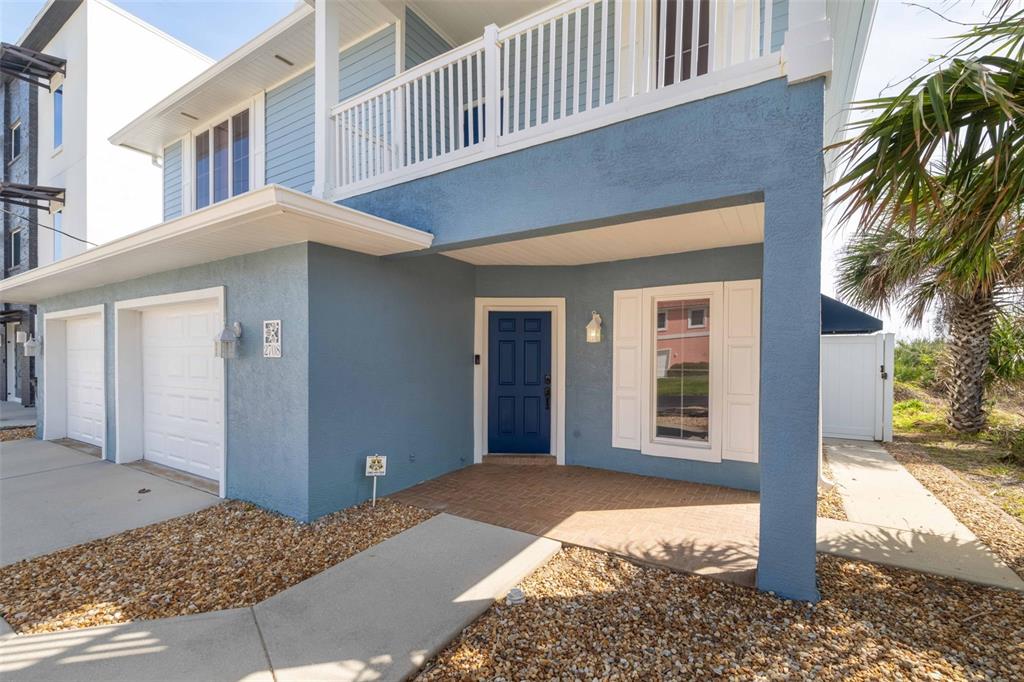 A blue two-story house features a brick porch, a dark blue front door, and a garage — 2708 S OCEAN SHORE BOULEVARD, FLAGLER BEACH, FL
