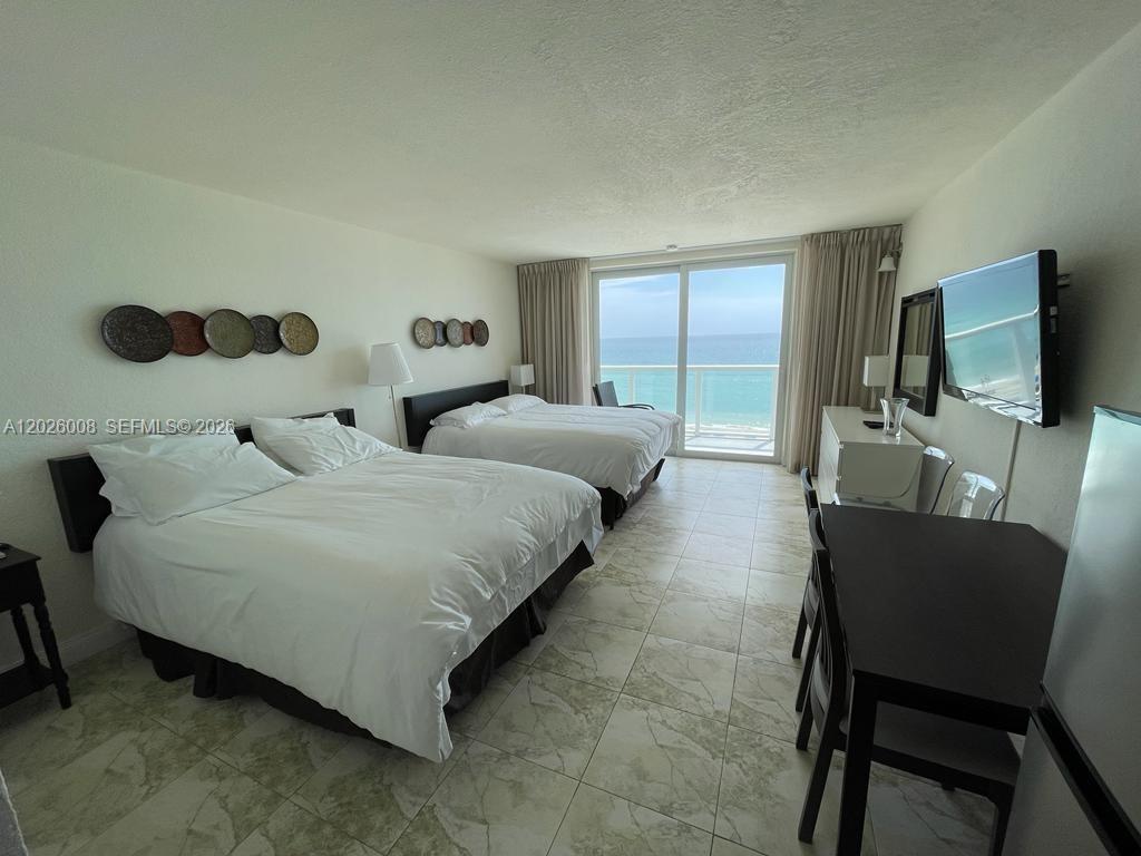 A hotel room features two beds, tile flooring, and a balcony overlooking the ocean — SUNNY ISLES BEACH, FL