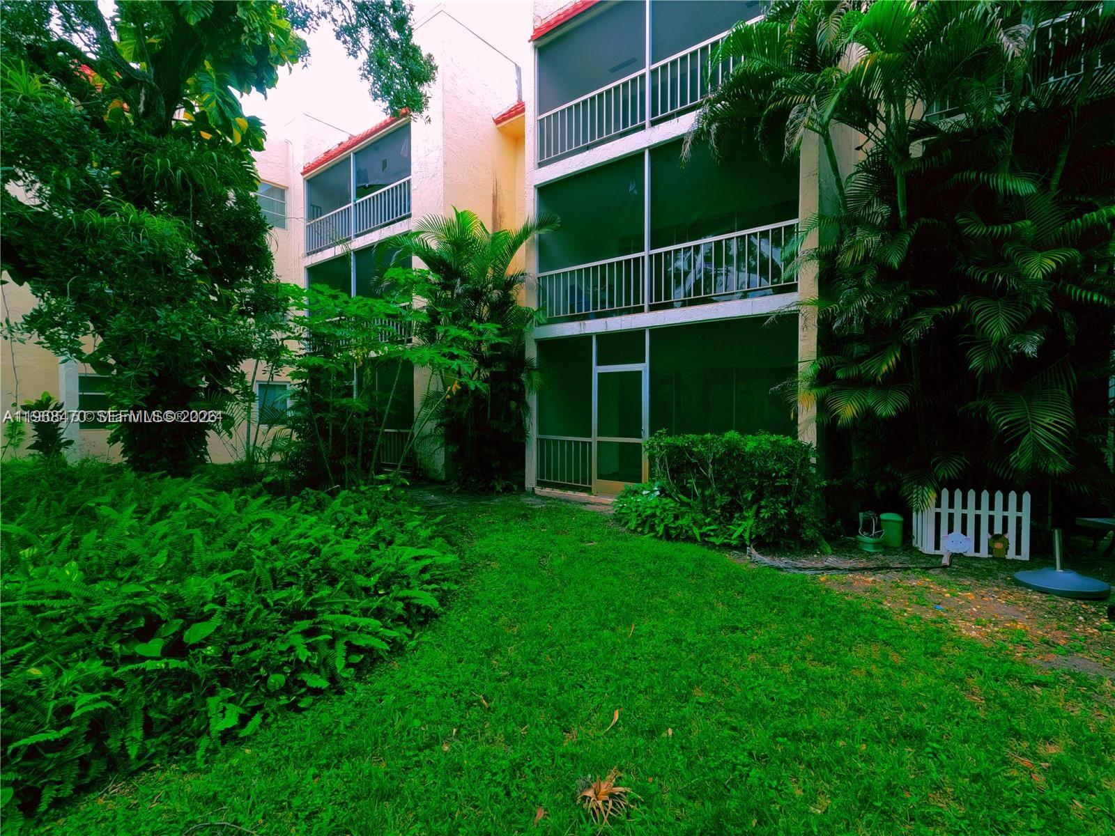 A three-story apartment building features screened balconies overlooking a lush green lawn and garden — 644 NW 13th St # 0120, Boca Raton FL 33486, BOCA RATON, FL