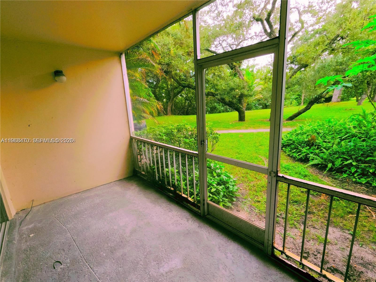 A screened-in patio features a concrete floor, a light fixture, and views of trees — 644 NW 13th St # 0120, Boca Raton FL 33486, BOCA RATON, FL