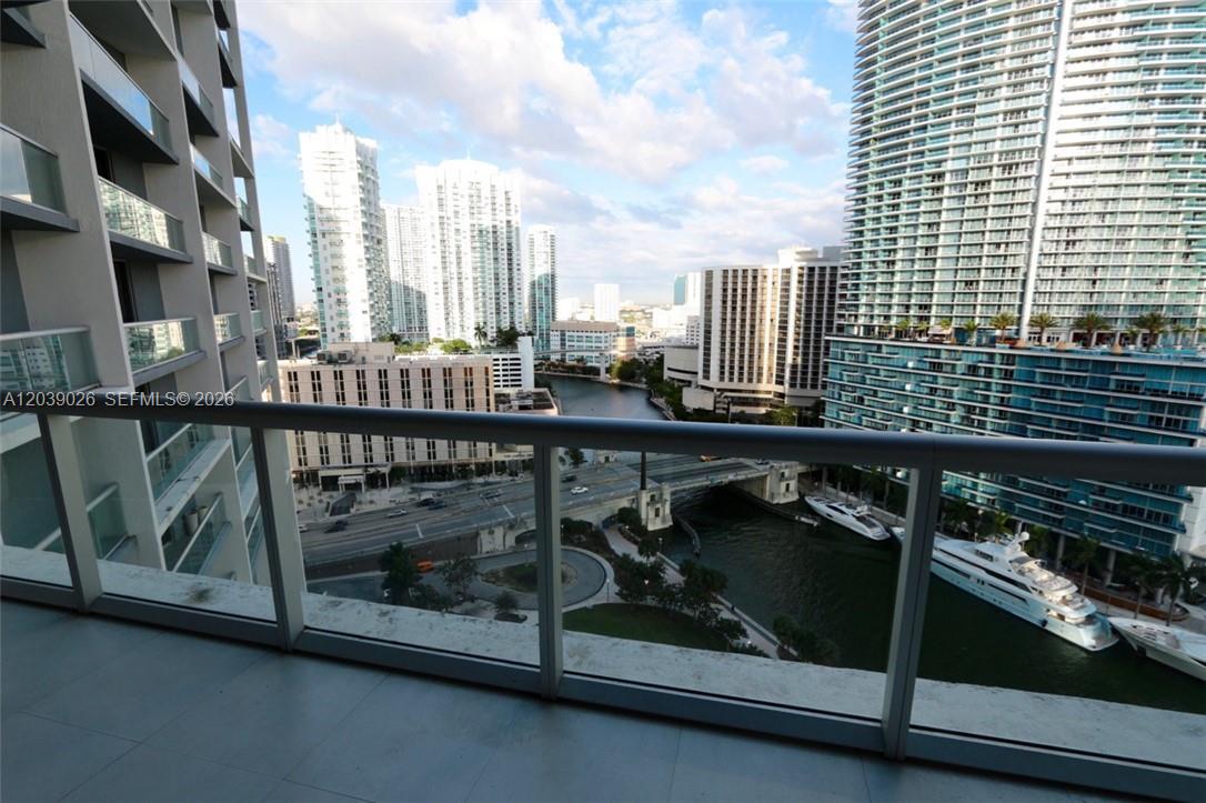 A high-rise balcony overlooks a city canal, a bridge, and surrounding residential skyscrapers — 465 Brickell Ave # 4706, Miami FL 33131, MIAMI, FL