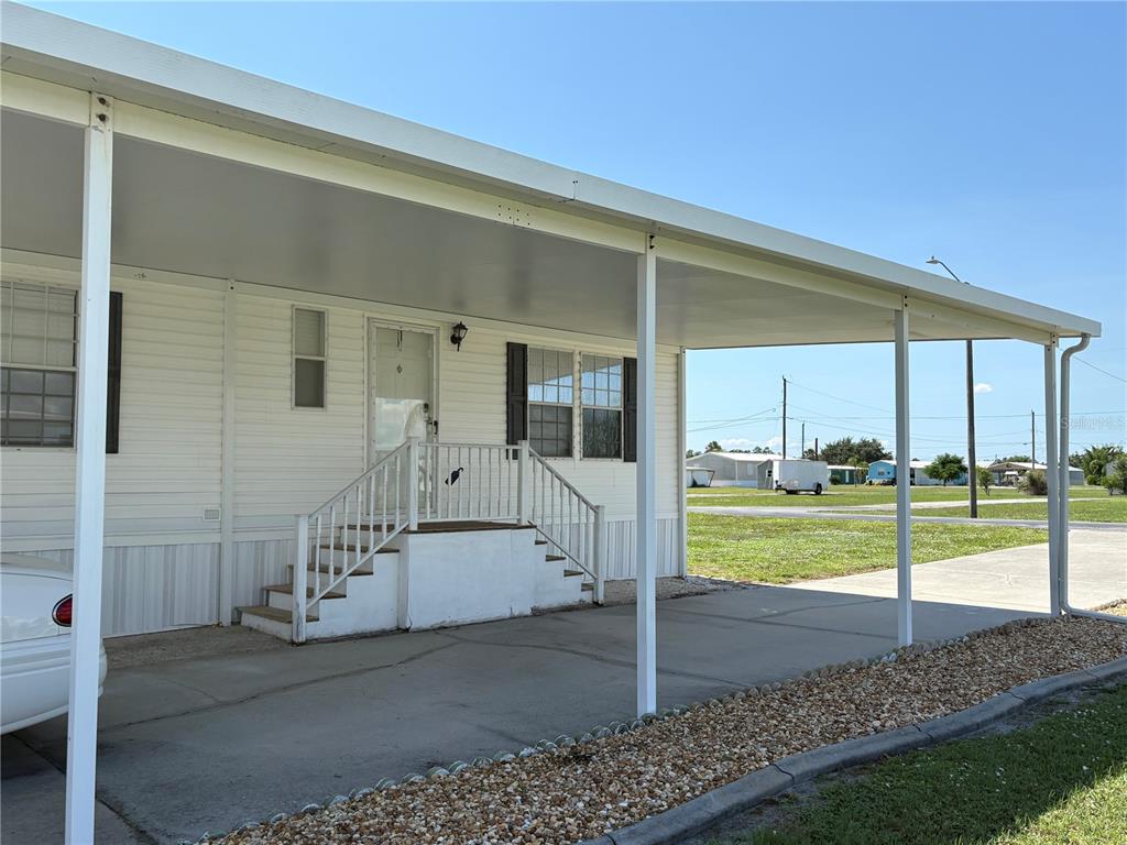 A white mobile home features a covered carport, concrete driveway, and a small front staircase — 29192 CRAWFORD AVENUE, PUNTA GORDA, FL