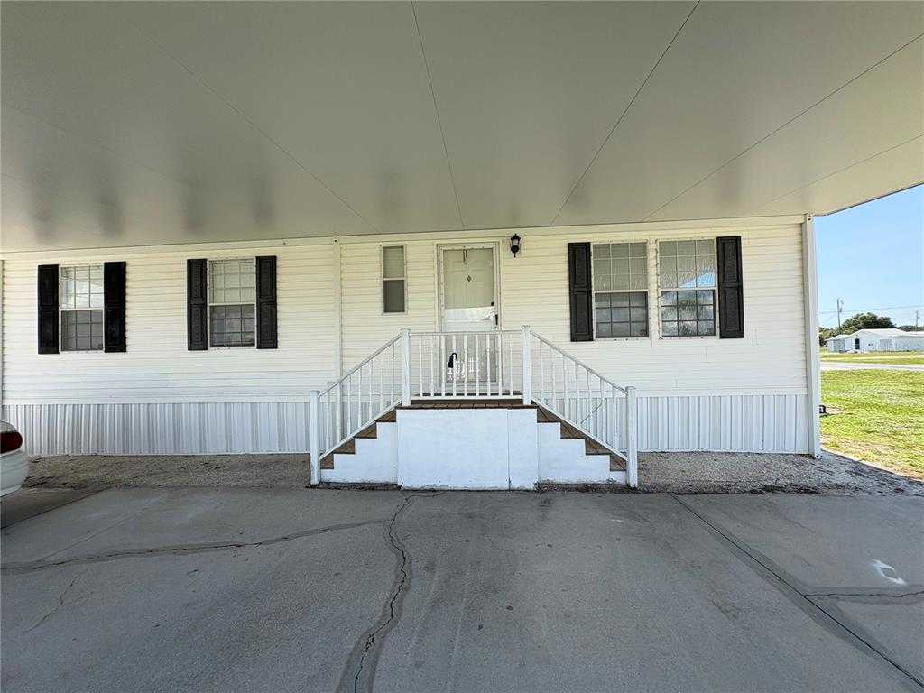 The exterior of a manufactured home features white siding, black shutters, and a covered carport — 29192 CRAWFORD AVENUE, PUNTA GORDA, FL