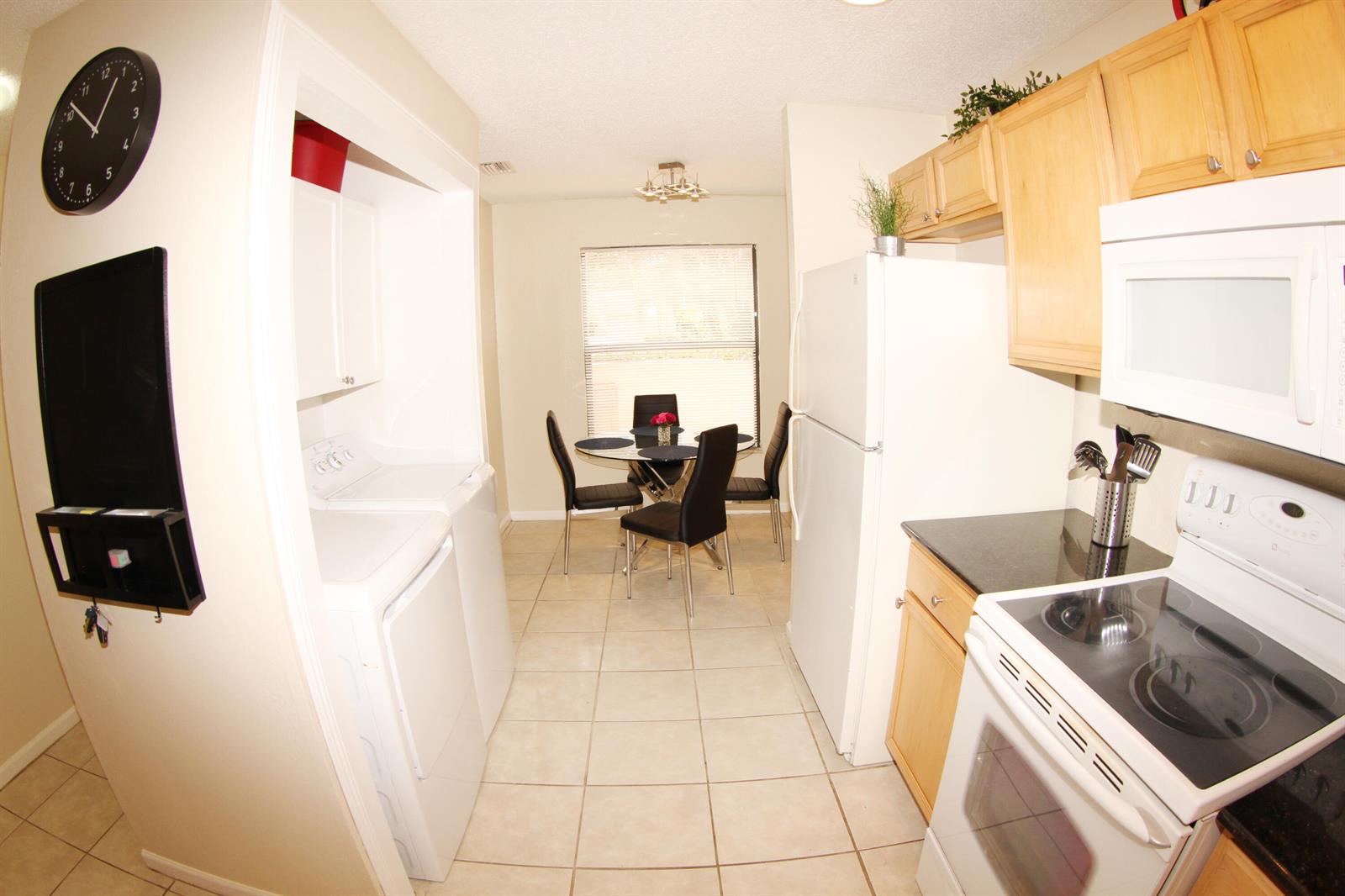 A kitchen with light wood cabinets, white appliances, and a dining area with tile flooring — 1308 White Pine Drive, Wellington FL 33414, WELLINGTON, FL