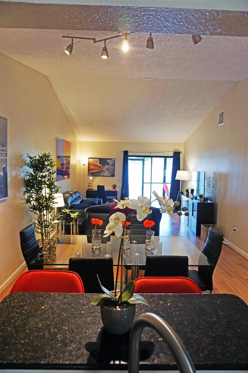 A dining area with a glass table and black chairs overlooks a living room space — 1308 White Pine Drive, Wellington FL 33414, WELLINGTON, FL