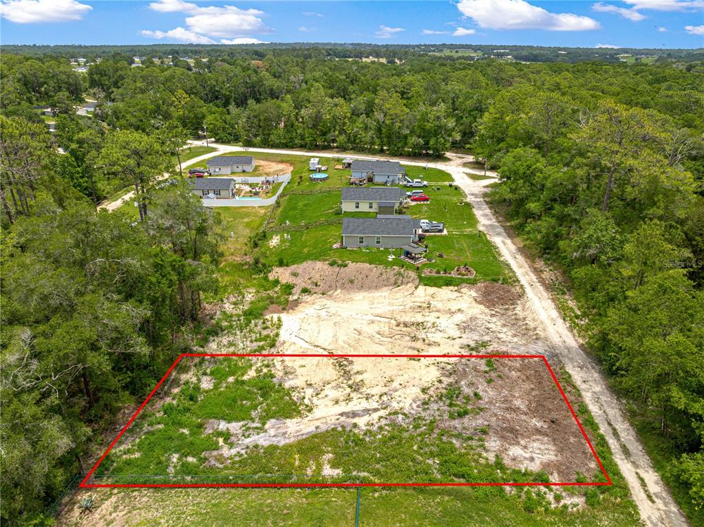 An aerial view shows a cleared, rectangular residential lot outlined in red next to a dirt road — SW 41ST STREET ROAD, OCALA, FL