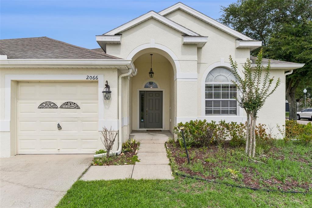 A single-story house with a beige stucco exterior, arched entryway, and an attached garage — 2066 GLORIA OAK COURT, ORLANDO, FL