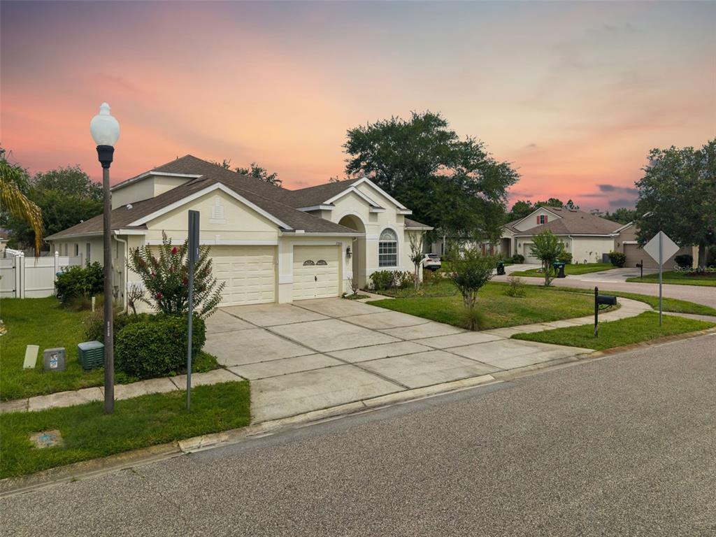 A single-story suburban house with a two-car garage and concrete driveway at sunset — 2066 GLORIA OAK COURT, ORLANDO, FL