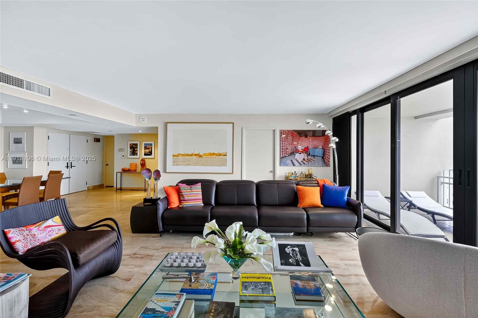A spacious living room features a leather sofa, glass coffee table, and large sliding glass doors — 2 Grove Isle Dr # B1804, Coconut Grove FL 33133, COCONUT GROVE, FL