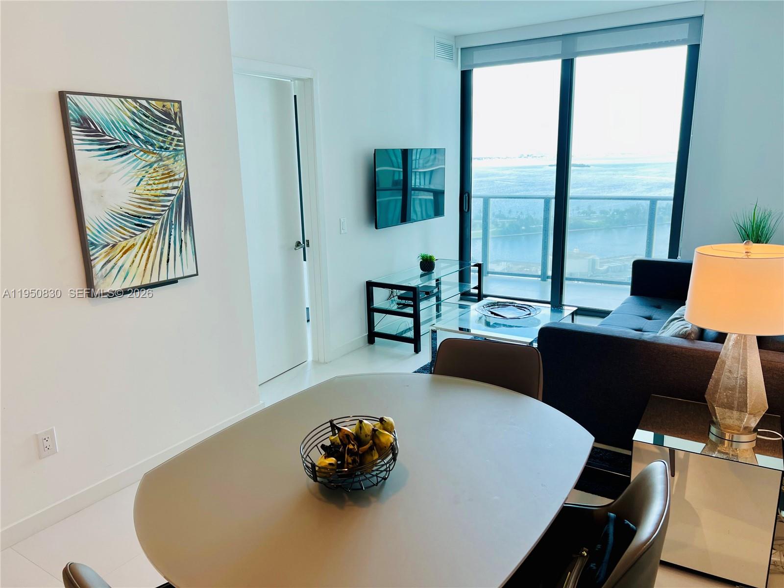 A dining area and living room with floor-to-ceiling windows overlooking a body of water — 501 NE 31st St # 2204, Miami FL 33137, MIAMI, FL