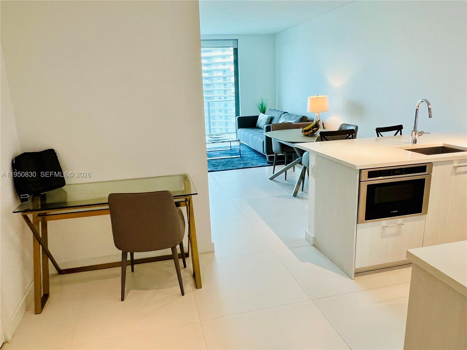 A modern kitchen island overlooks a dining area and living room with floor-to-ceiling windows — 501 NE 31st St # 2204, Miami FL 33137, MIAMI, FL