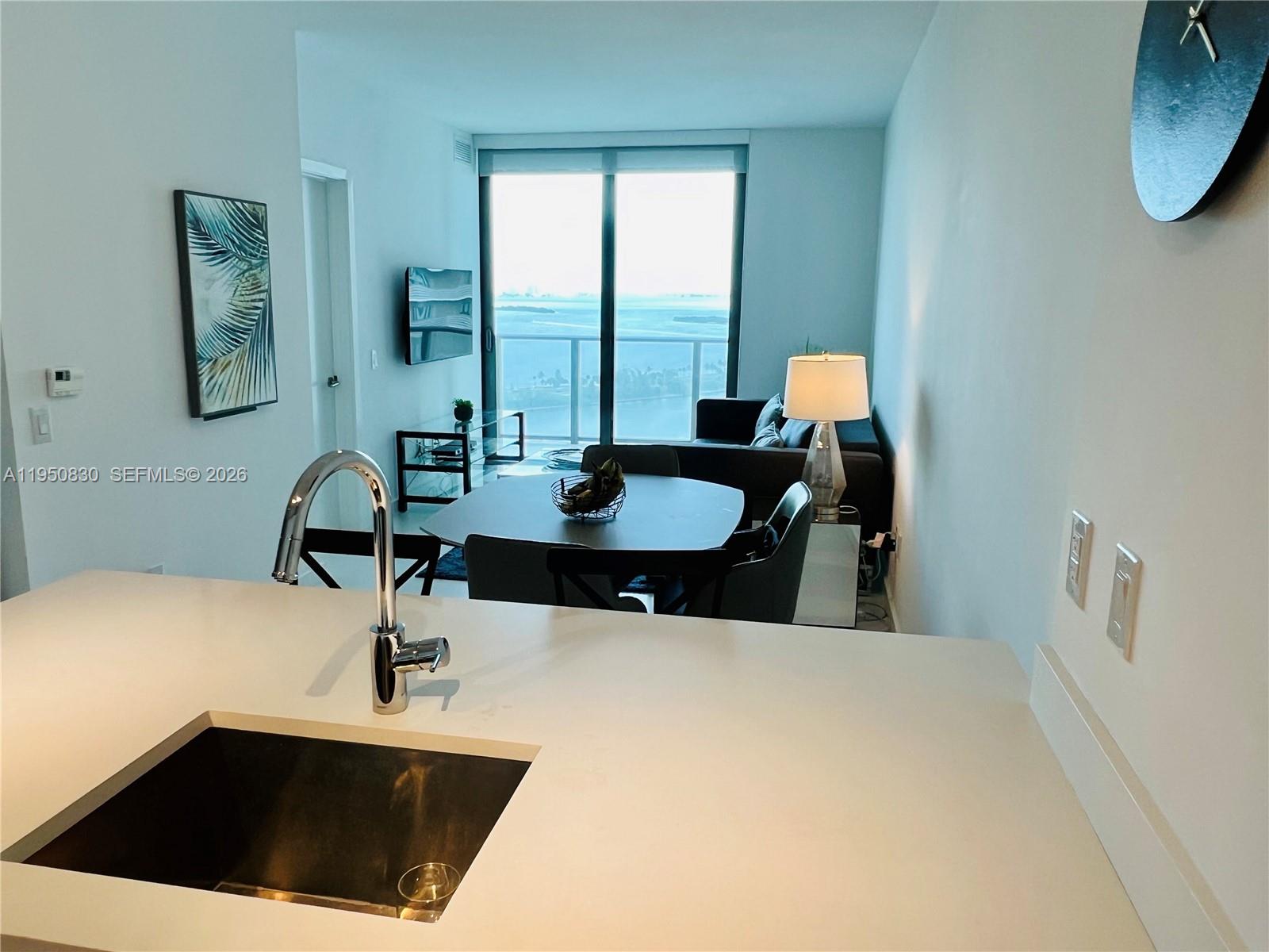 A kitchen island with a sink overlooks a dining area and living room with water views — 501 NE 31st St # 2204, Miami FL 33137, MIAMI, FL