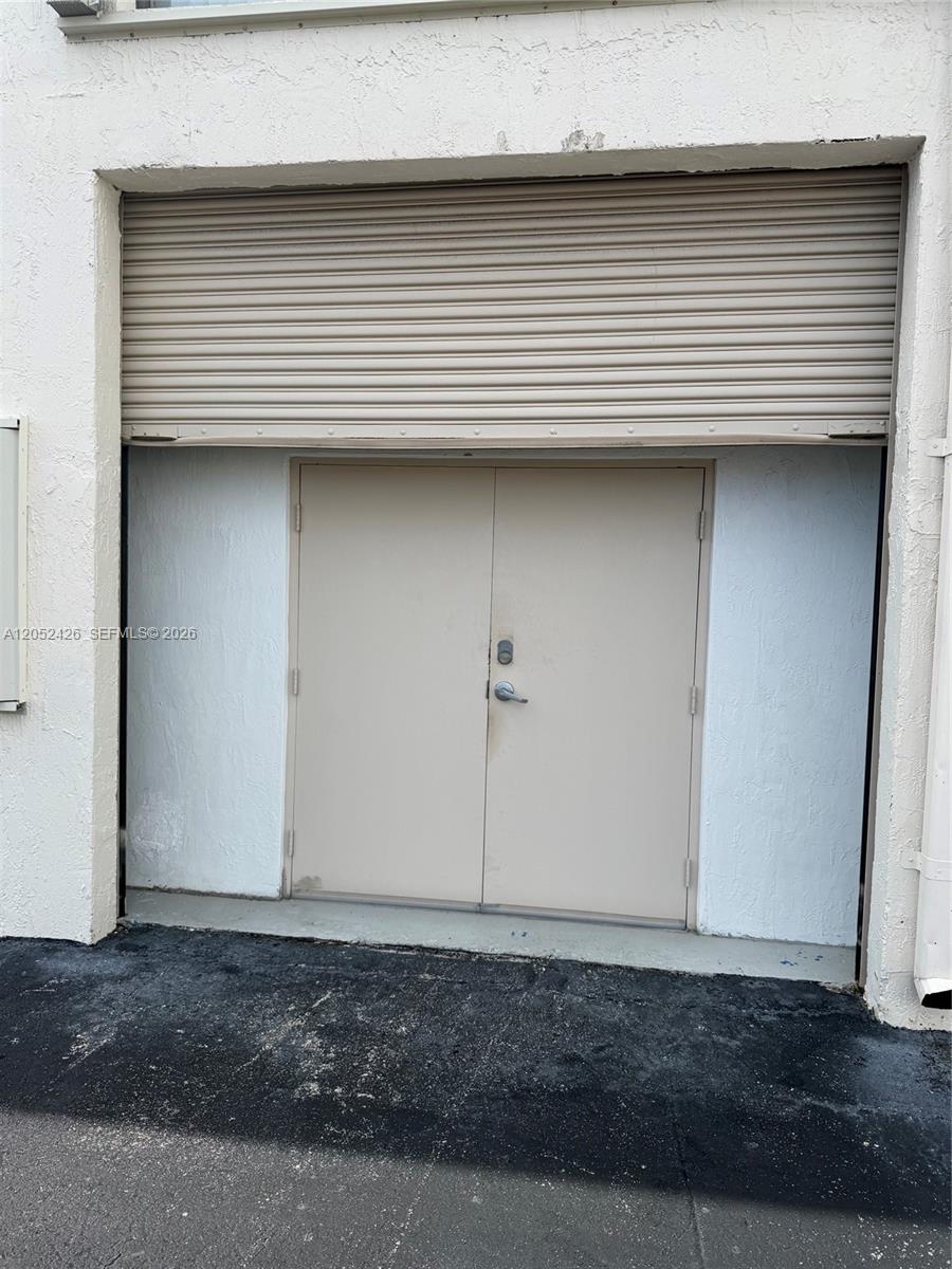 A pair of beige double doors is situated beneath a metal roll-up security shutter — 13889 SW 140th St # 547, Miami FL 33186, MIAMI, FL