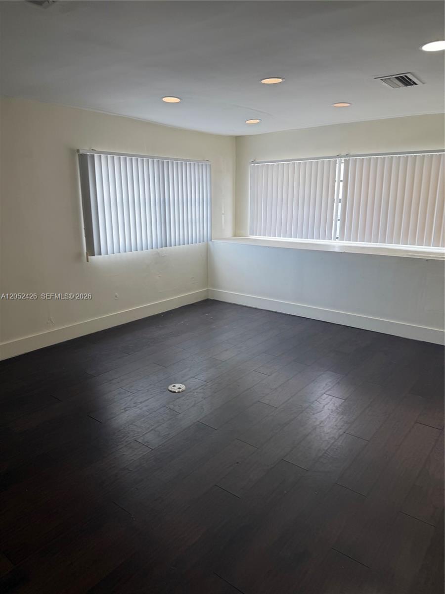 An empty room features dark wood flooring, white walls, recessed lighting, and vertical window blinds — 13889 SW 140th St # 547, Miami FL 33186, MIAMI, FL