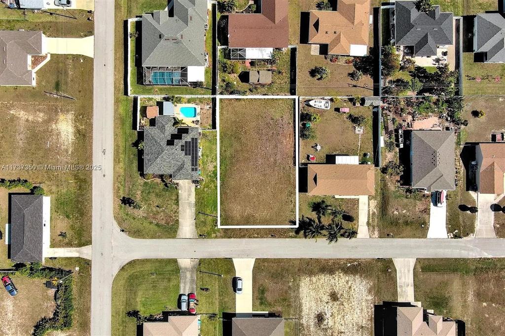 This aerial view shows a vacant rectangular residential lot situated between two existing houses — 2013 NE 18TH AVENUE, CAPE CORAL, FL